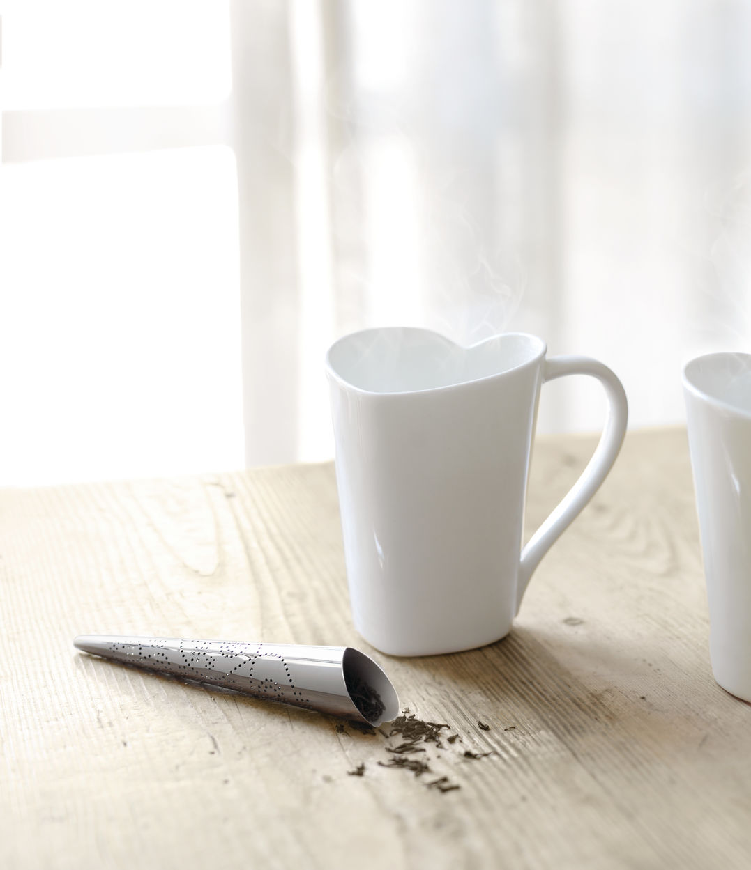 Alessi You thee-ei naast hartvormige mok met dampende thee