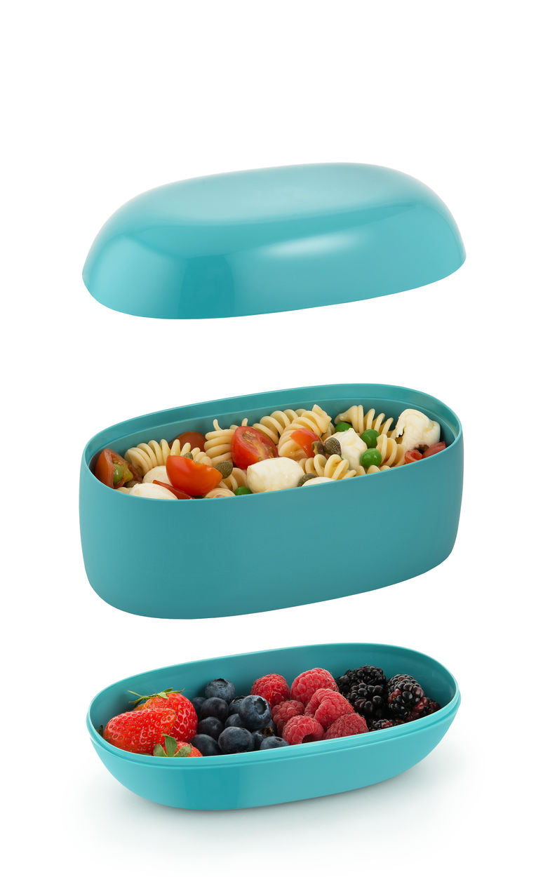 Alessi bento-box in blauw, gestapelde vakken gevuld met fruit en pasta