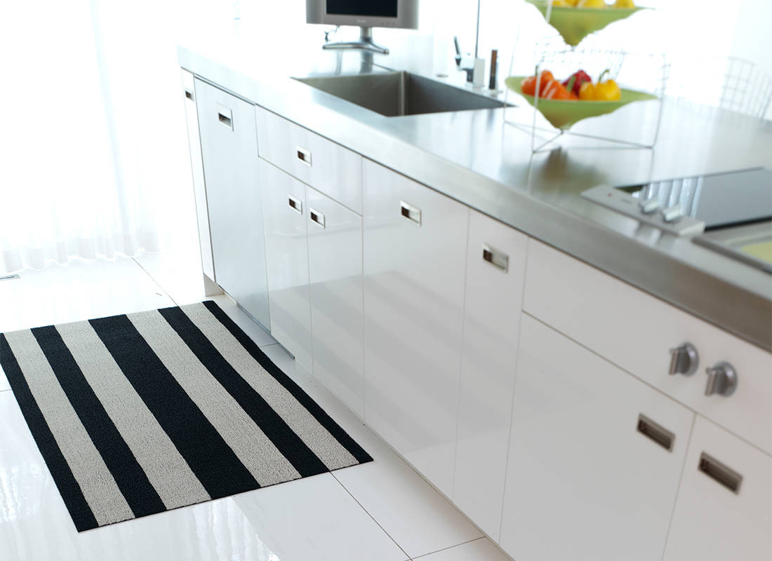 Chilewich doormat in black and white, placed by kitchen cabinets