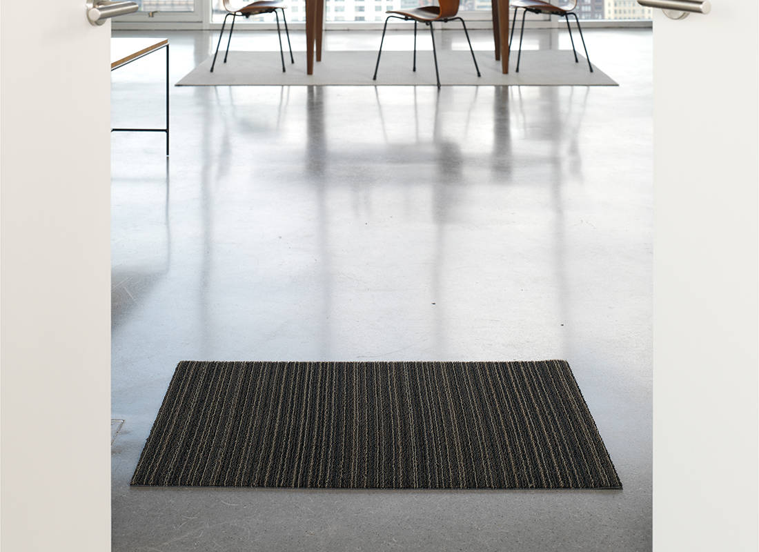 Chilewich deurmat Skinny Stripe Steel, ontwerp Sandy Chilewich, op vloer voor tafel
