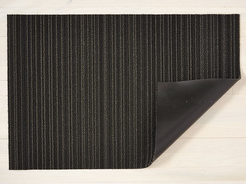 Chilewich deurmat Skinny Stripe Steel, omgeslagen hoek toont vinyl onderlaag