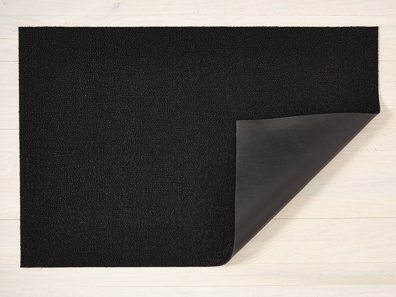 Chilewich Solid Black deurmat, omgevouwen hoek toont vinyl onderlaag