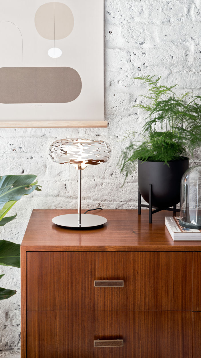 Alessi Barklamp, rvs tafellamp, brandend op dressoir, zijaanzicht