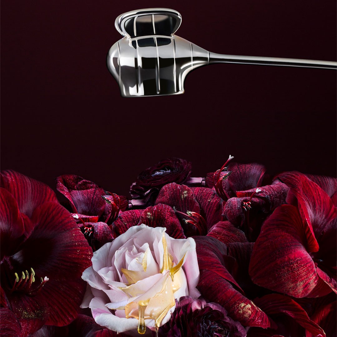 Red and pink flowers with silver-coloured candle snuffer, illustrating the 'Hmm' fragrance composition