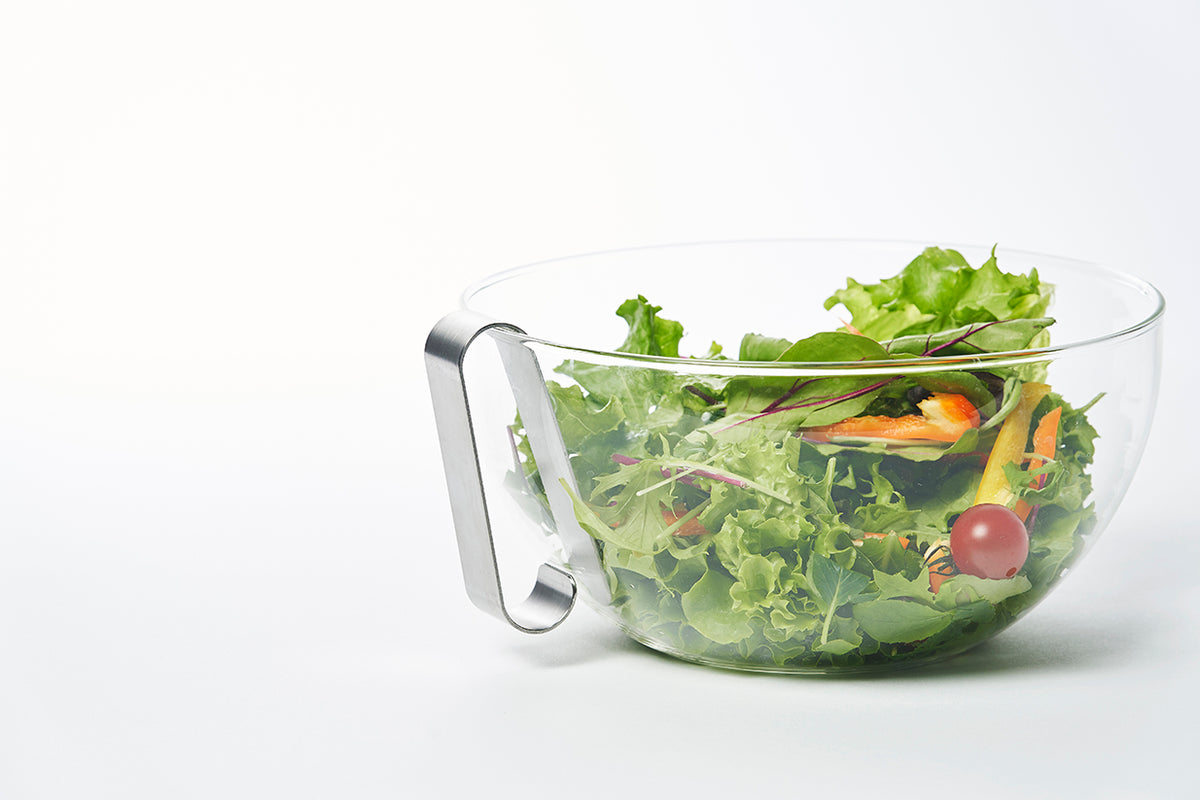Oros Handy kleine rasp, hangend aan de rand van een schaal met salade.