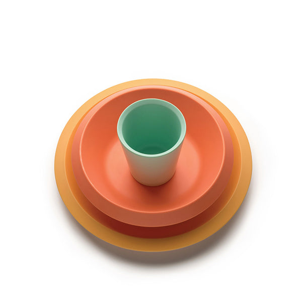 Alessi Giro kinderservies van UN Studio, met beker, groot bord en diep bord in oranje en groen.
