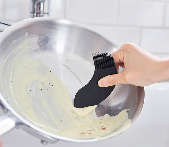 +D Happy schraper, zwart, in gebruik bij kookpan met beslag