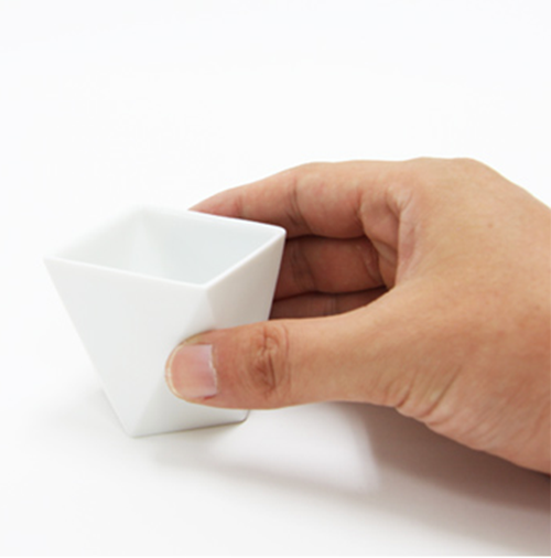 Detail van een Shuki sake-kopje van Alessi, vastgehouden in een hand
