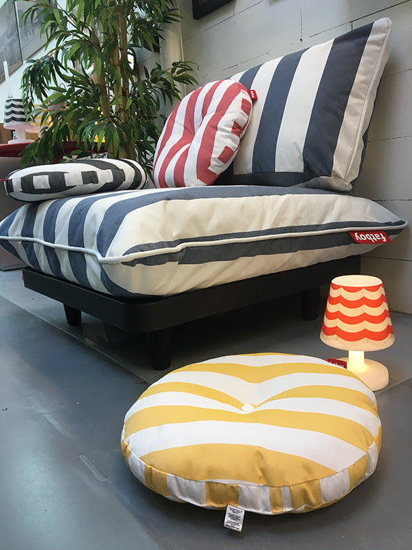 Ronde kussens in blauw-wit, rood-wit en geel-wit gestreept naast elkaar op een loungebank
