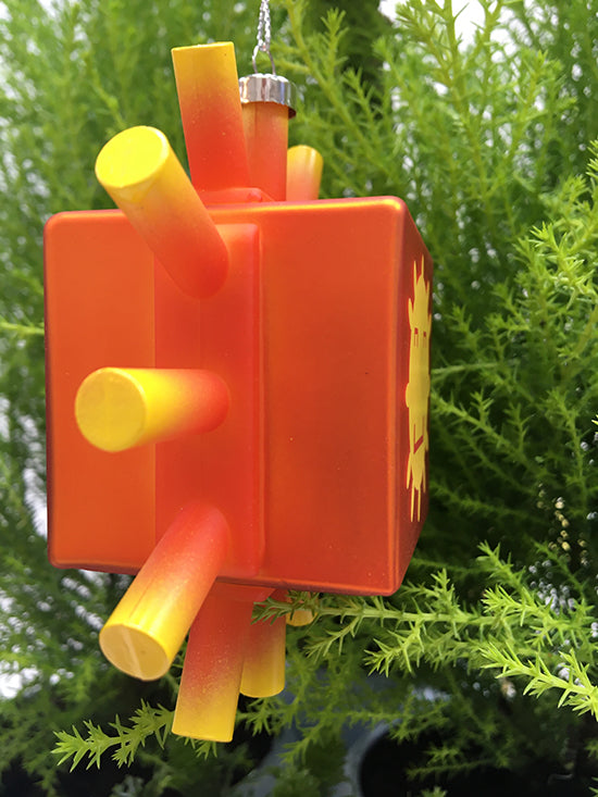 Alessi Sunflake kerstkubus, kerstbal in geel-oranje, gedeeltelijk zonmotief zichtbaar