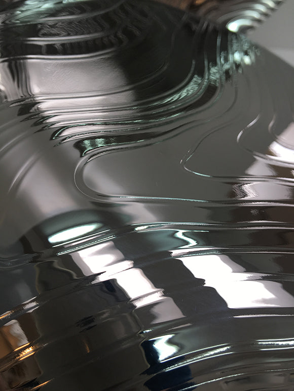 Detail van het gepolijste oppervlak van de Alessi Veneer schaal met houtnerf-patroon