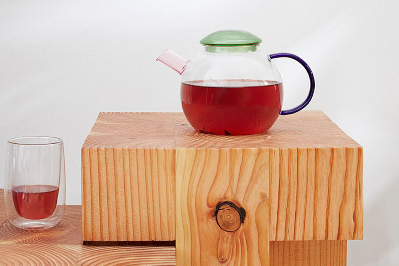 Glazen theepot gevuld met thee, naast een doppler glas