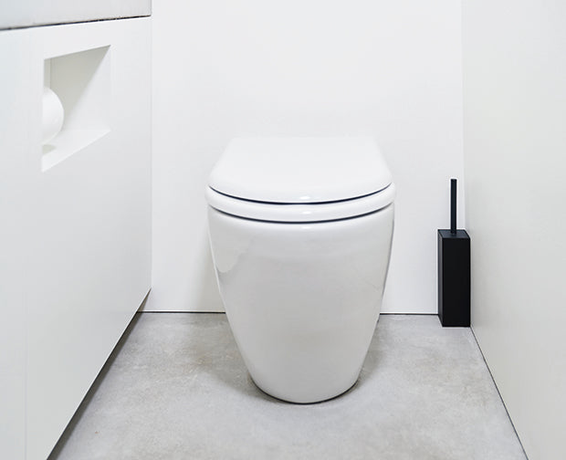 Japanse toiletborstel in zwarte houder, vrijhangend naast het toilet