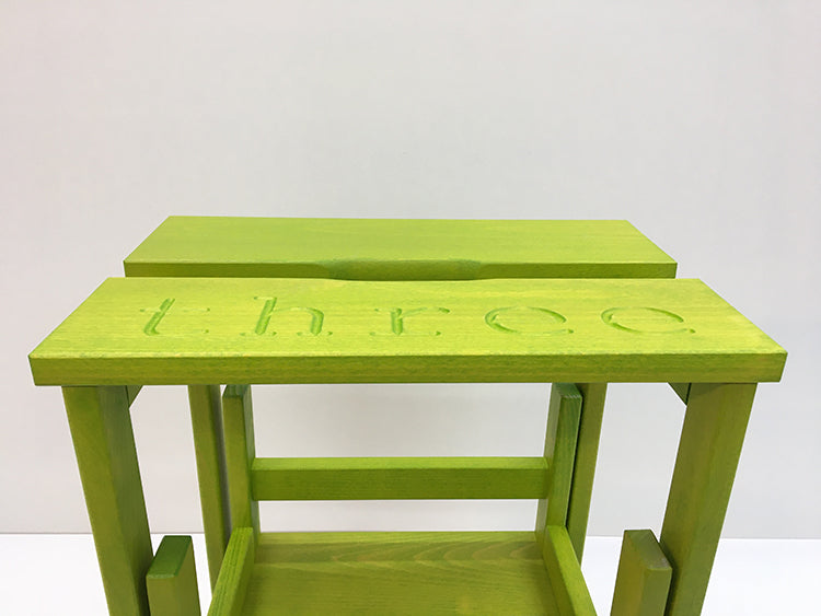 Detail van boventrede met gravering Three van Happy Numbers opstapkrukje in acid green