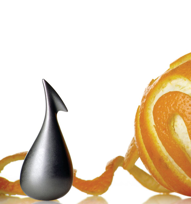 Alessi Apostrophe dunschiller, druppelvormig, naast een geschilde sinaasappel
