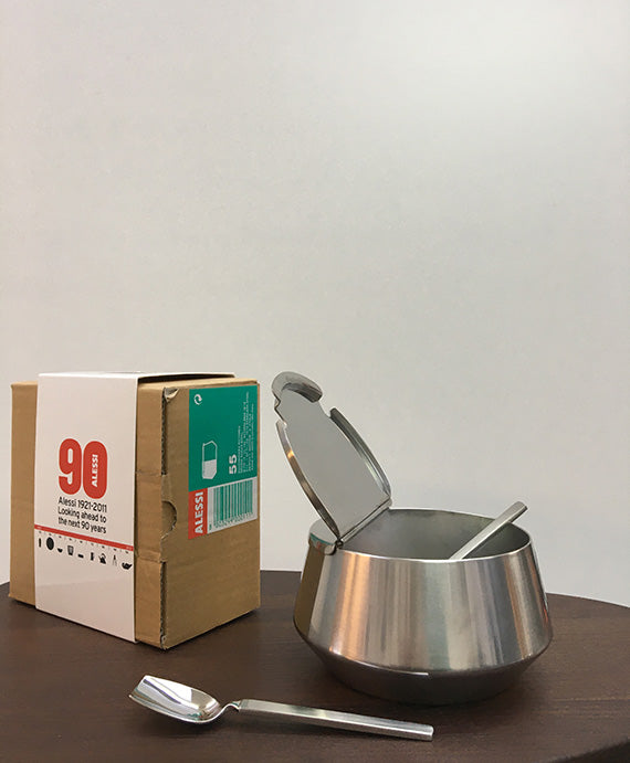 Alessi suikerpot met geopend deksel en lepeltje, naast verpakking