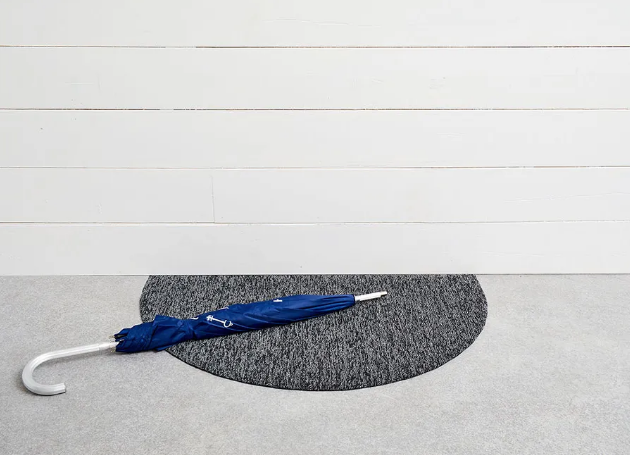 Semi-circular doormat in grey, top view with umbrella on it