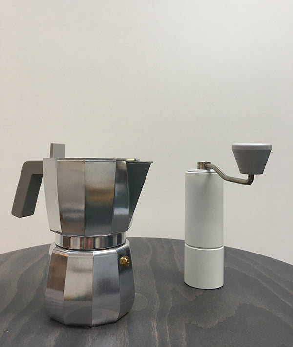 Witte koffiemolen naast een moka-pot, ter grootte-vergelijking.