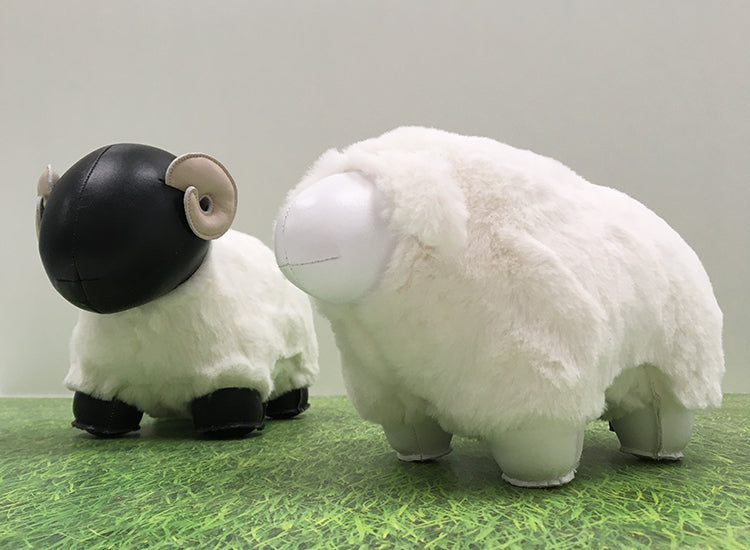 Zijaanzicht van zwart-wit schapenbeeldje en wit schapenbeeldje naast elkaar