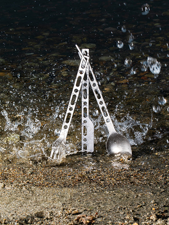 Mes, lepel en vork van de Alessi Occasional Object bestekset rechtop bij water