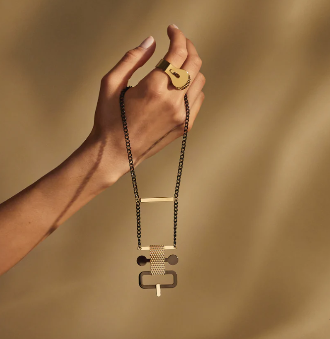 Edone halsketting van Alessi, gedragen aan de hand, in goud en zwart