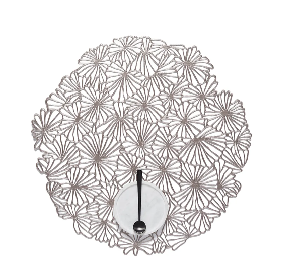Placemat Daisy Vinyl van Alessi in gunmetal, licht gebogen, met lepel erop.