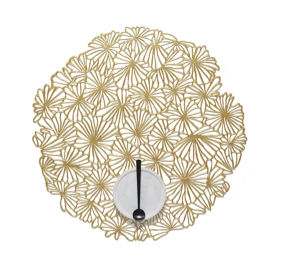 Placemat van Sandy Chilewich met goudkleurig bloemmotief, schaal en lepel erop
