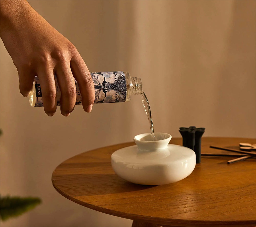 Navulling van de Alessi Grrr-diffuser: fles huisparfum wordt in de witte houder gegoten