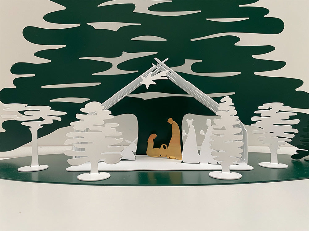 Alessi Bark witte boompjes rond een kerststal met gouden figuren.