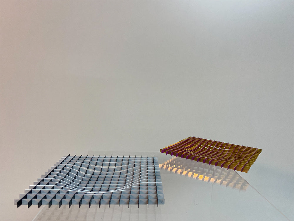 Metalen fruitschaal Gravity in goud en magenta naast grijze variant
