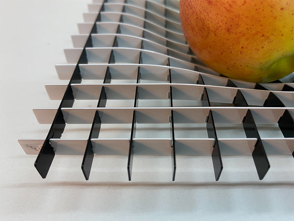 Detail van het metalen roosterpatroon van de Gravity fruitschaal, met appel