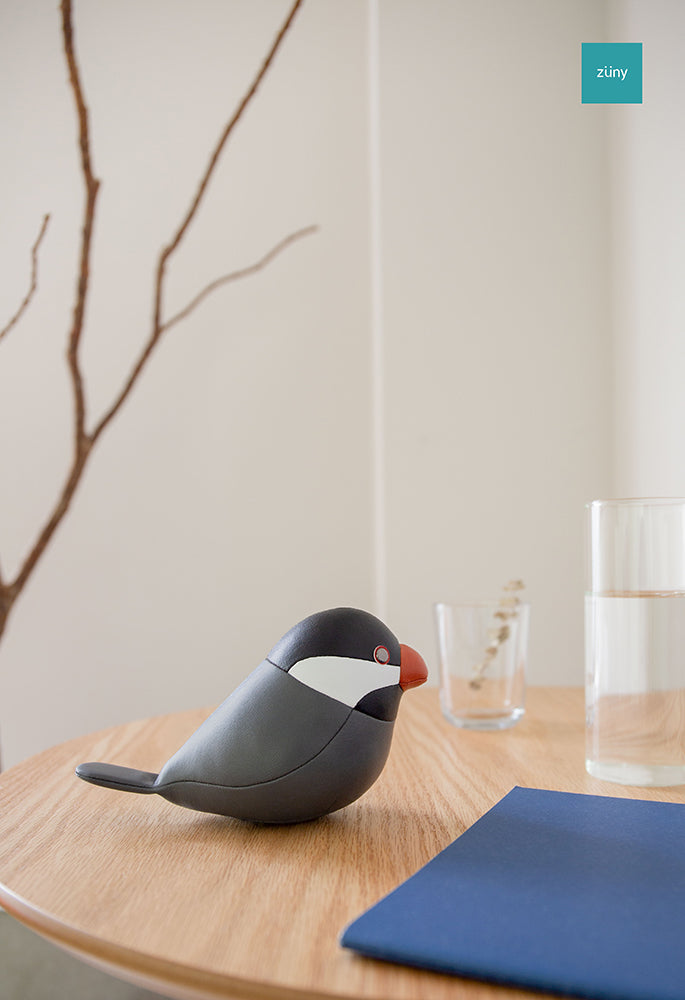 Zuny rice bird paperweight next to a glass and notebook