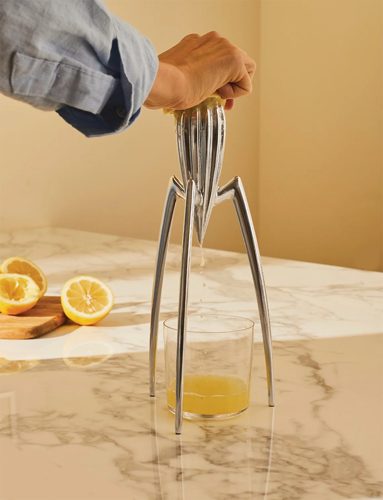 Juicy Salif citruspers in gebruik, hand perst citroen boven glas