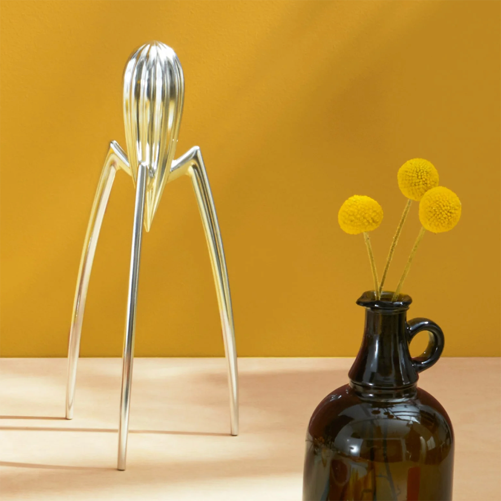 Juicy Salif citruspers, aanzicht vanaf de zijkant naast een karaf