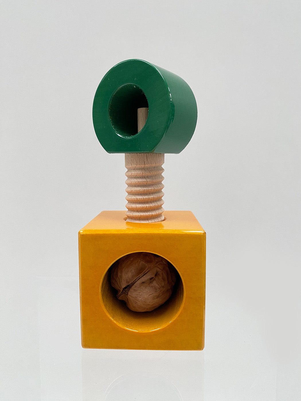 Alessi Twergi notenkraker van Ettore Sottsass in groen en geel, vooraanzicht met walnoot in de onderkant