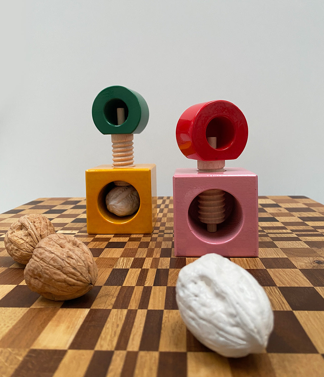 Twee Alessi Twergi notenkrakers, groen-geel en rood-roze, met walnoten
