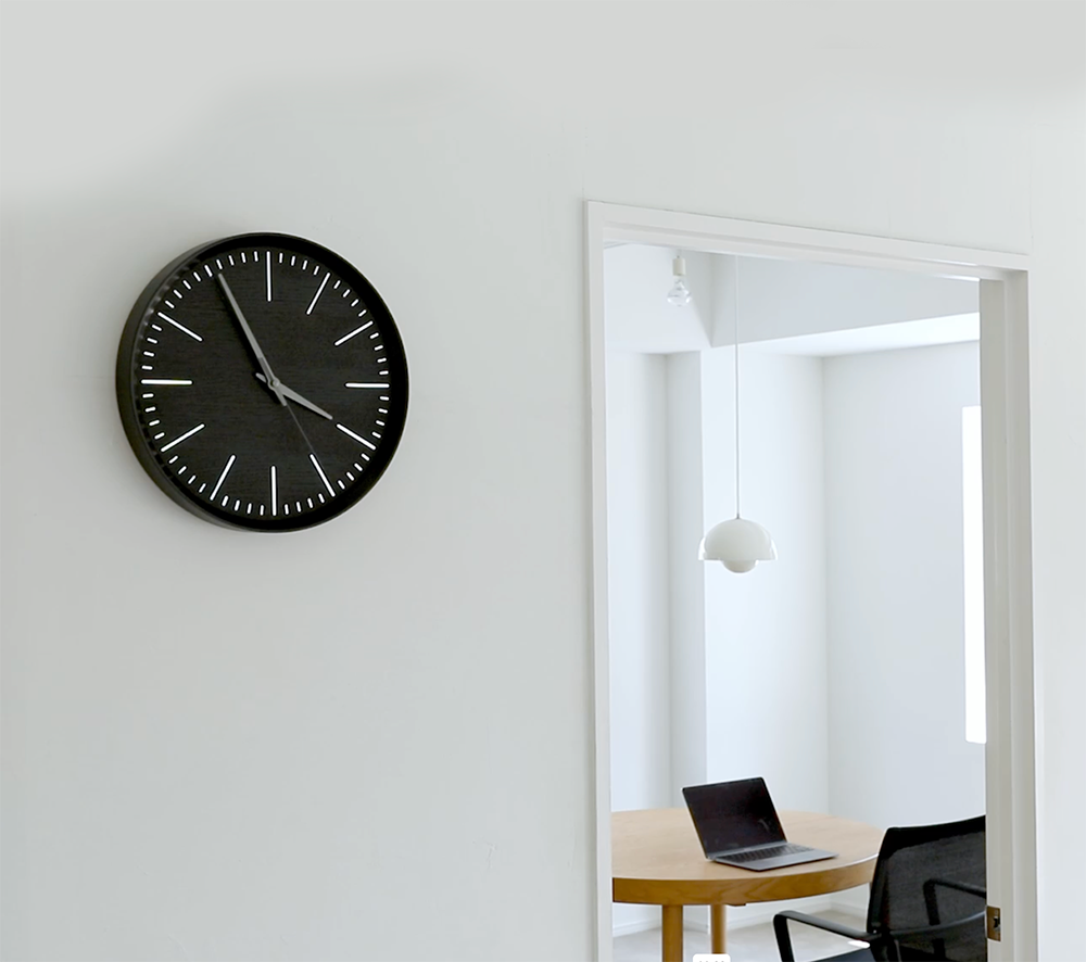 Lemnos Fluct houten wandklok in zwart, opgehangen aan de muur