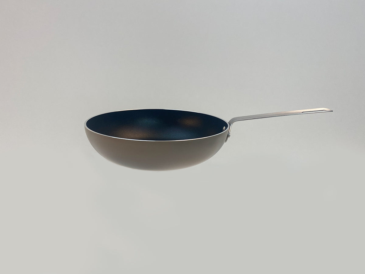 Zijaanzicht van de Alessi TAMA wok in taupe met donkerblauwe binnenzijde