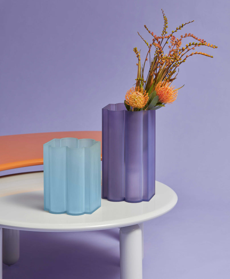 Okra vaas van Kartell, laag en lichtblauw naast paarse variant met bloemen