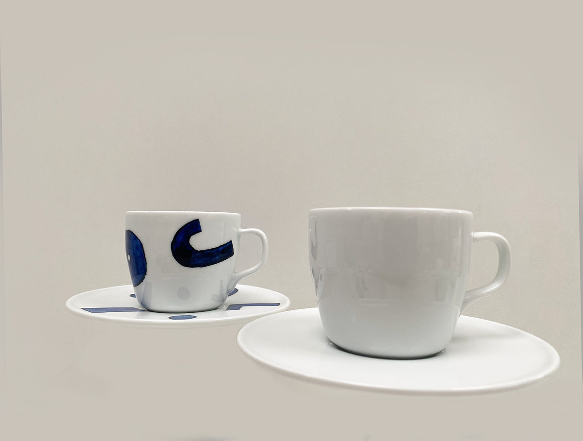 Twee koffiekoppen met schotel naast elkaar: gedecoreerde en witte versie.
