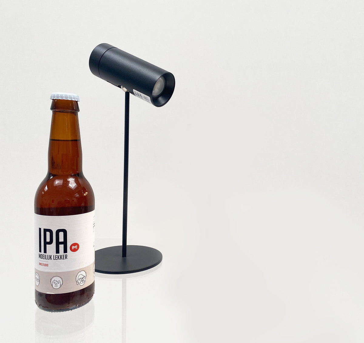 SIA tafellamp in mat zwart, naast flesje ter grootte-indicatie
