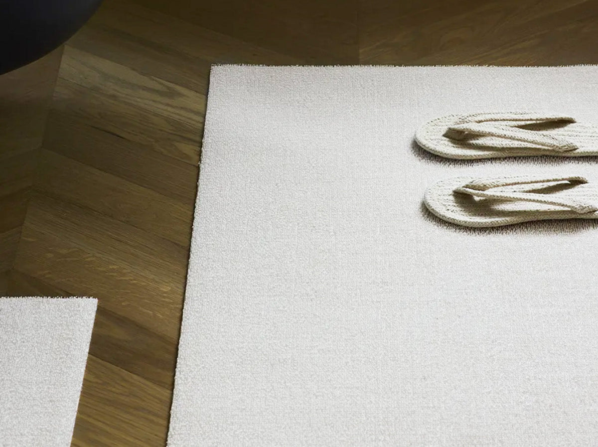Chilewich deurmat Utility superwit op houten vloer, met slippers