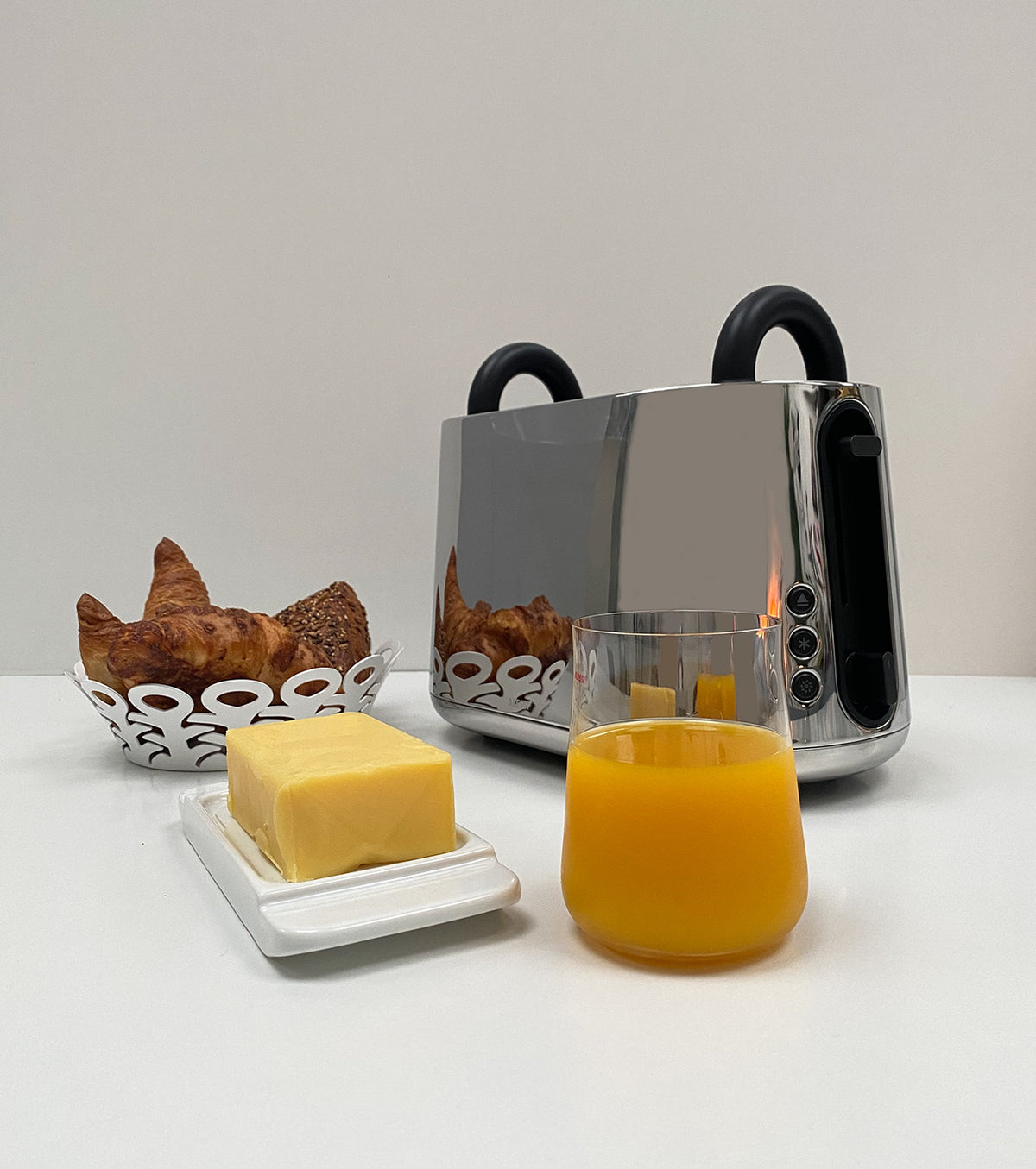 Alessi Toru broodrooster in rvs, tweede vooraanzicht met croissants en boter