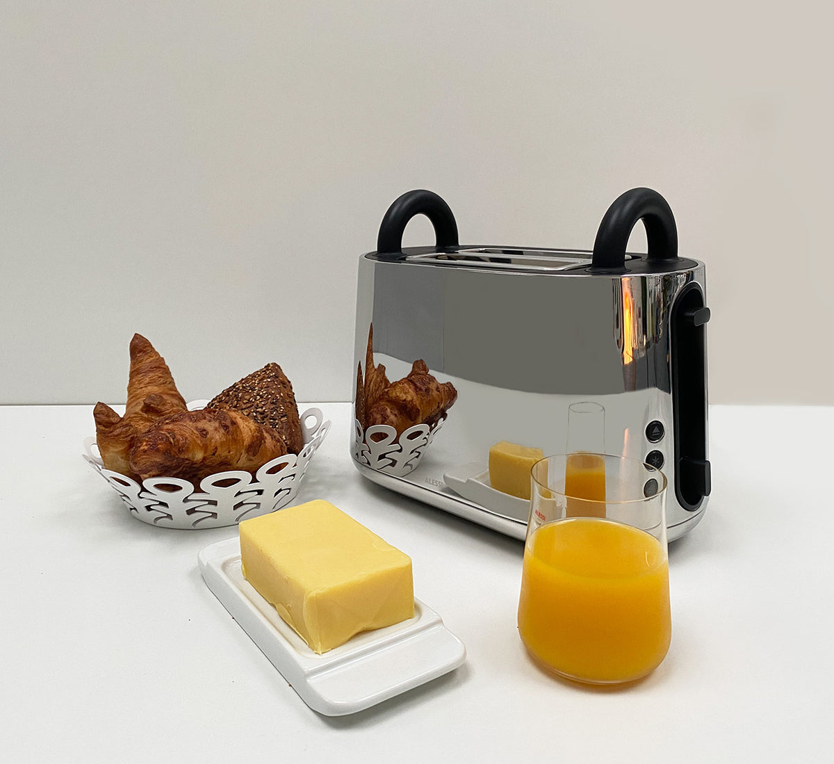 Alessi Toru broodrooster in rvs, vooraanzicht met croissants en jus d'orange