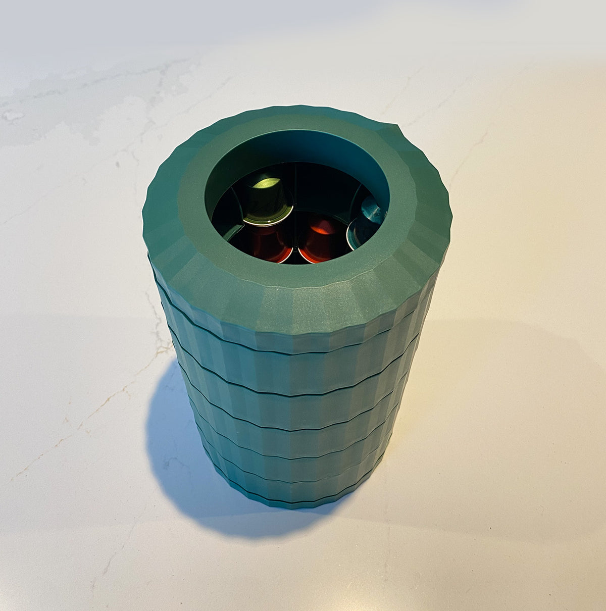 Plissé capsulehouder van Alessi in groen, schuin bovenaanzicht met capsules zichtbaar