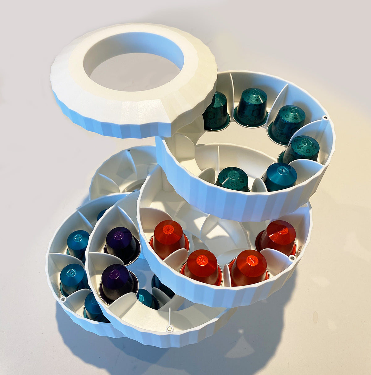 Alessi Plissé capsulehouder in wit, geopend met compartimenten vol koffiecapsules