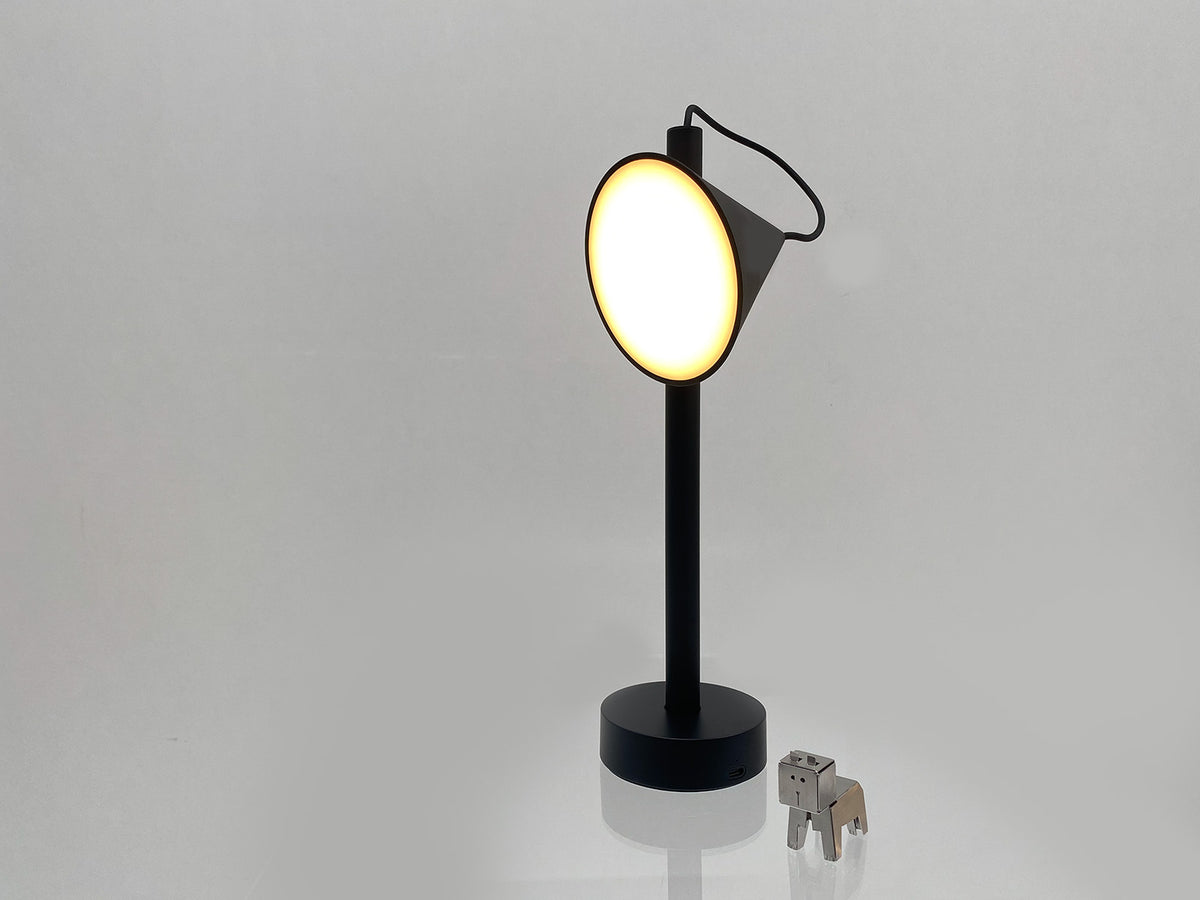 Tsumiki tafellamp van Alessi in zwart, vooraanzicht met brandend licht
