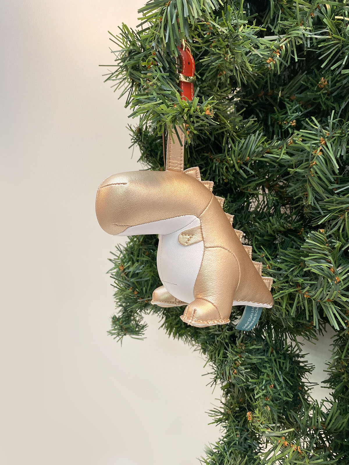 Dino Bobo kerstboomhanger van Zuny in goud kunstleer met rood/groene leren band
