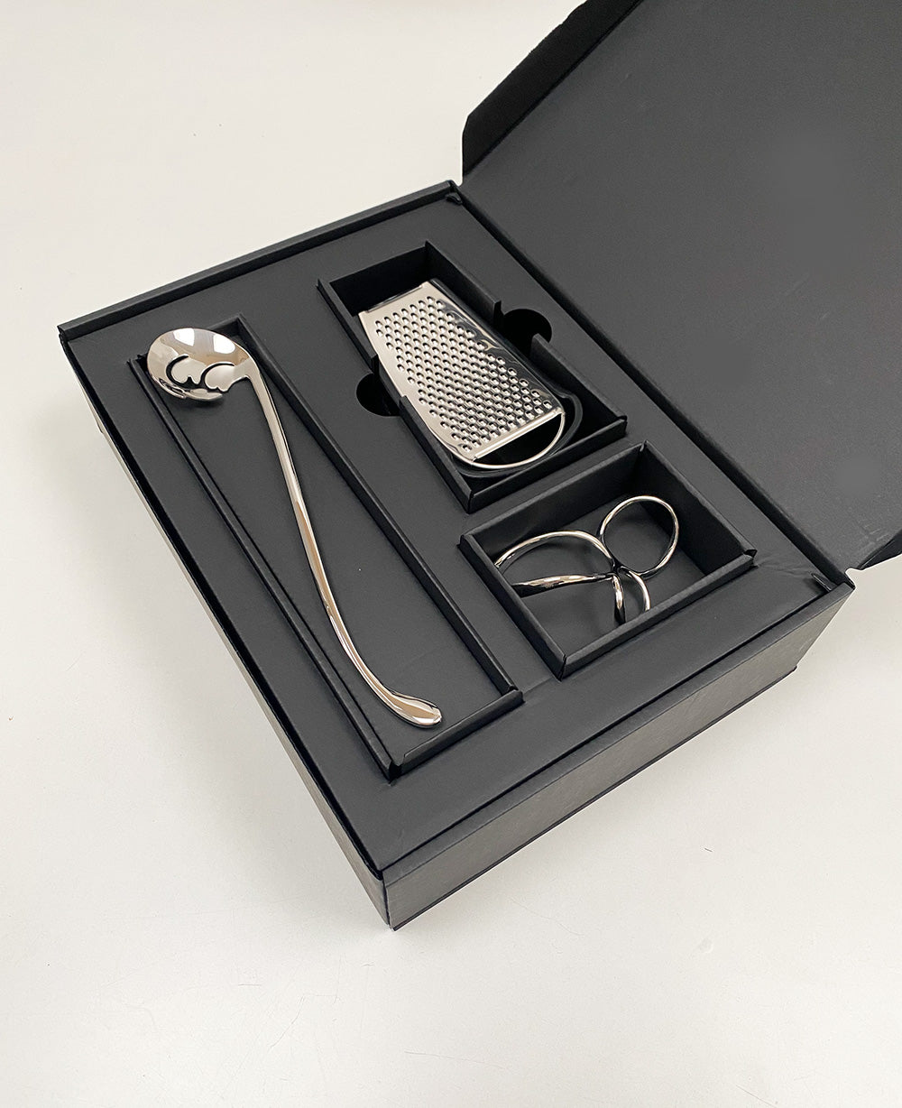 Geopende geschenkdoos met pastalepel, kaasrasp en spaghettimeter in vakken