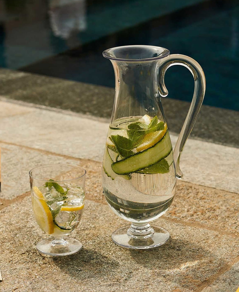 Glas Dressed En Plein Air van Alessi, gevuld met drank naast schenkkan